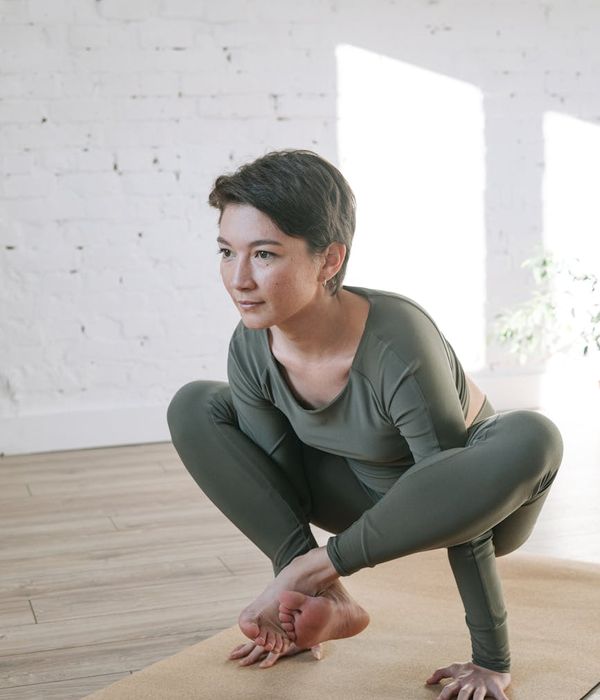 Woman in a peaceful yoga pose in a bright, serene room.
